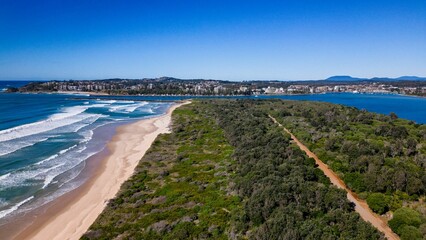 Aerial view of a road surrounded by green nature near the North Shore beach, Australia