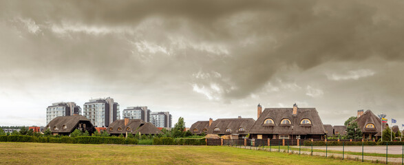 Panoramic view of the block of houses with reed roofs in Sventoji during the summer on cloudy day. Lithuania.
