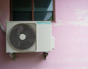 The air conditioner compressor is installed on the wall near the window.