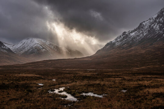 Majestic dramatic Winter sunset sunbeams over landscape of Lost Valley in Etive Mor in Scottish Highlands
