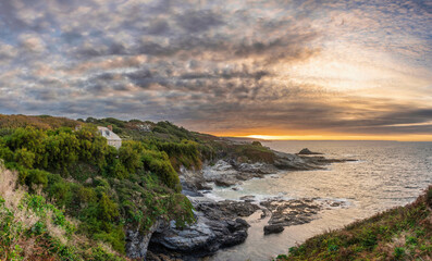 Dramatic landscape sunrise image at Prussia Cove in Cornwall England with atmospheric sky and ocean