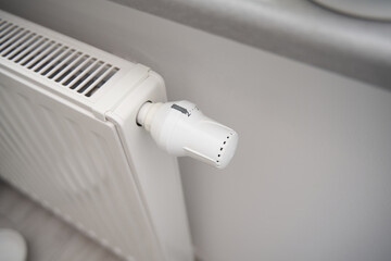 Close-up of turning down the thermostat on a radiator to save energy due to heating cost price...