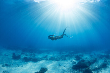 Women having fun underwater snorkeling in shallow clear waters with sunrays in the ocean