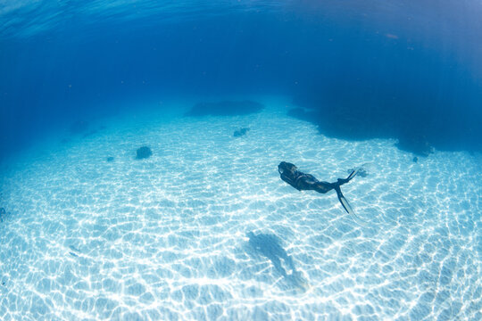 Women having fun underwater snorkeling in shallow clear waters with sunrays in the ocean