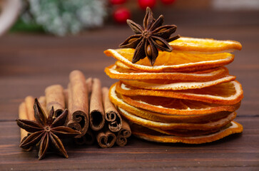 Spicy spices on a wooden table close-up. Cinnamon sticks, anise stars and a stack of dried oranges.