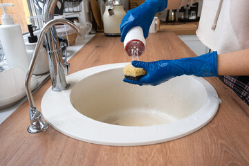 Cleaning sink in kitchen, Hand in gloves and sponge, detergent, dry powder. cozy interior of the home, restoring order, cleanliness, disinfection