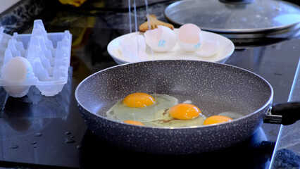 man cooks fried eggs in a teflon pan, pour refined palm oil into the pan. Cooking process of tasty healthy food.