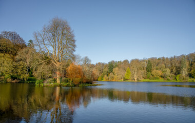 autumn afternoon sunshine illuminates woodland and the island in the lake, Stourhead estate Wiltshire UK