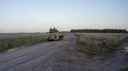 Fototapeta premium British army Warrior FV510 Fighting Vehicle in action driving on a mud track on a military battle exercise, Wiltshire UK