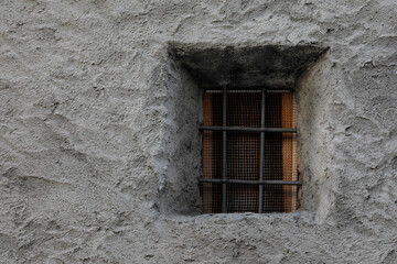 Grey concrete house wall with small lattice window,
no person with space for background