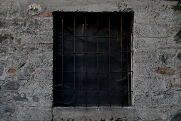 Fototapeta na wymiar Grey brick houswall with closed window, frame with bars and lattice, no person