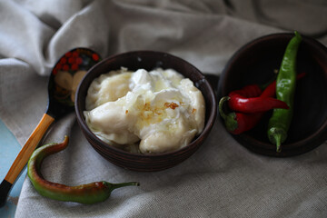 boiled hot dumplings in a clay pot with fried onions and sour cream and hot peppers
