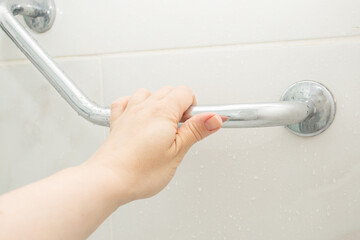 hand holding the handrail in the shower, safe bathing for the elderly and people with limited...