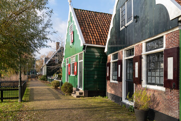 Fototapeta na wymiar Green painted wooden small houses in the historic Zaanse neighborhood in the municipality of Zaanstad in the Netherlands.
