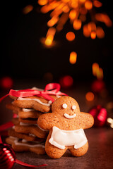 Homemade baked sweet and spicy gingerbread cookies in form of man and stars flavored with ginger, cloves and cinnamon served at festive Christmassy table with sparkling bokeh lights at Christmas Eve