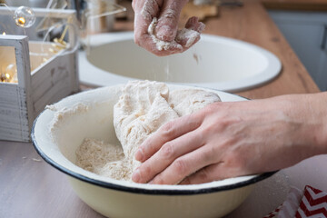 Hands knead thick dough on the kitchen table, decorated with festive decorations for Christmas and New year. Baking at home, aroma and comfort. Close-up