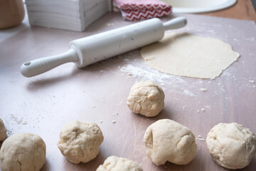 Hands knead thick dough, roll out with a rolling pin on the kitchen table, decorated with festive decorations for Christmas and New year. Baking at home, aroma and comfort. 