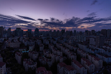 Cloudy rose blue sunset over dark silhouettes of city buildings, top view. Evening view. High quality photo