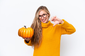 Young blonde woman holding a pumpkin isolated on white background proud and self-satisfied