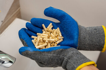 hands of a worker hold in their palms a bunch of plastic dowel pins