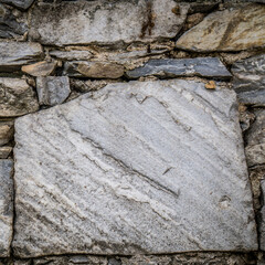 A stonewall made with gray granite slabs cut to various sizes.