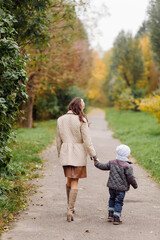 Mom and son walking and having fun together in the autumn park.