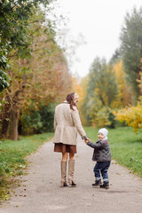 Obraz premium Mom and son walking and having fun together in the autumn park.