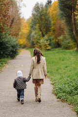 Fototapeta premium Mom and son walking and having fun together in the autumn park.