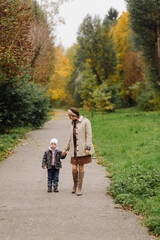 Mom and son walking and having fun together in the autumn park.