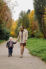 Fototapeta premium Mom and son walking and having fun together in the autumn park.