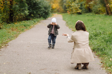 Fototapeta premium Mom and son walking and having fun together in the autumn park.