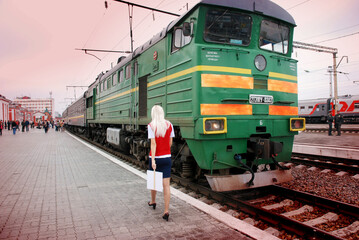 An electric train train arrives at the railway station of a small town in the summer