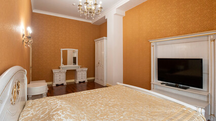 A bedroom in yellow tones with a large bed and TV in front of it.