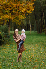 Fototapeta premium Mom and son walking and having fun together in the autumn park.
