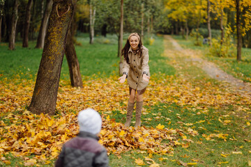 Mom and son walking and having fun together in the autumn park.