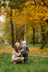 Fototapeta na wymiar Mom and son walking and having fun together in the autumn park.