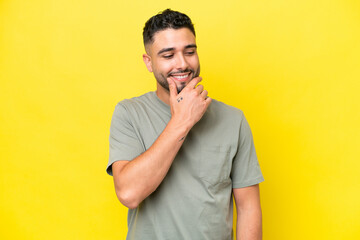 Young Arab handsome man isolated on yellow background looking to the side and smiling