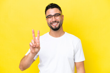 Young Arab handsome man isolated on yellow background With glasses and doing OK sign