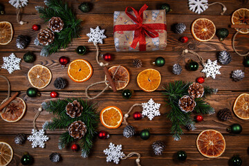 Christmas background. Gift in vintage packaging, dried oranges, Christmas toys and branches, Christmas decor on a wooden table.