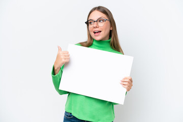 Young caucasian woman isolated on white background holding an empty placard and pointing side