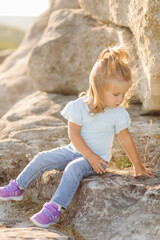 Beautiful mother and her cute long haired daughter are walking on meadow of stone