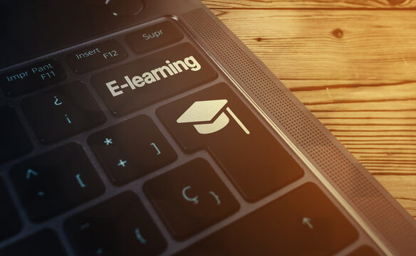 Laptop keyboard with E-learning word on button and graduation cap. Webinar. Online education. Distance courses.