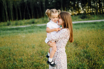 Happy family in a park in summer autumn. Mother, father and baby play in nature in the rays of sunset