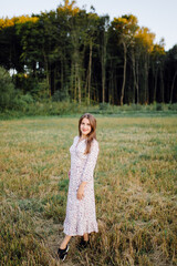 Young woman with beautiful hair posing in field at sunset. Fashion, independence