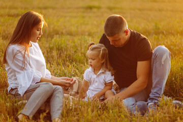 Happy family in a field in autumn. Mother, father and baby play in nature in the rays of sunset.