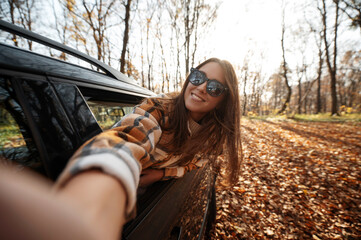 Pov of the woman making selfie from the car window during the autumn road trip
