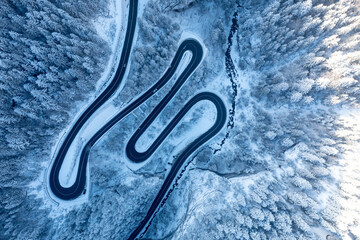Carpathian, Romania, 2021-12-28. Aerial view of a mountain road under snow.