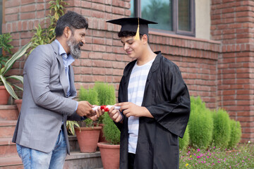 Chancellor of university giving diploma to graduating student, successful future