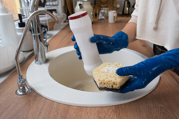 Cleaning sink in kitchen, Hand in gloves and sponge, detergent, dry powder. cozy interior of the...
