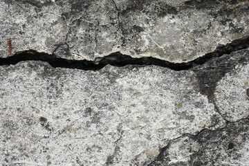 An old wall made of reinforced concrete with cracks in it
